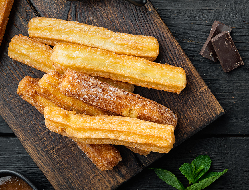 Churros with caramel Traditional Spanish cusine, on black wooden table background, top view flat lay with space for text, copyspace